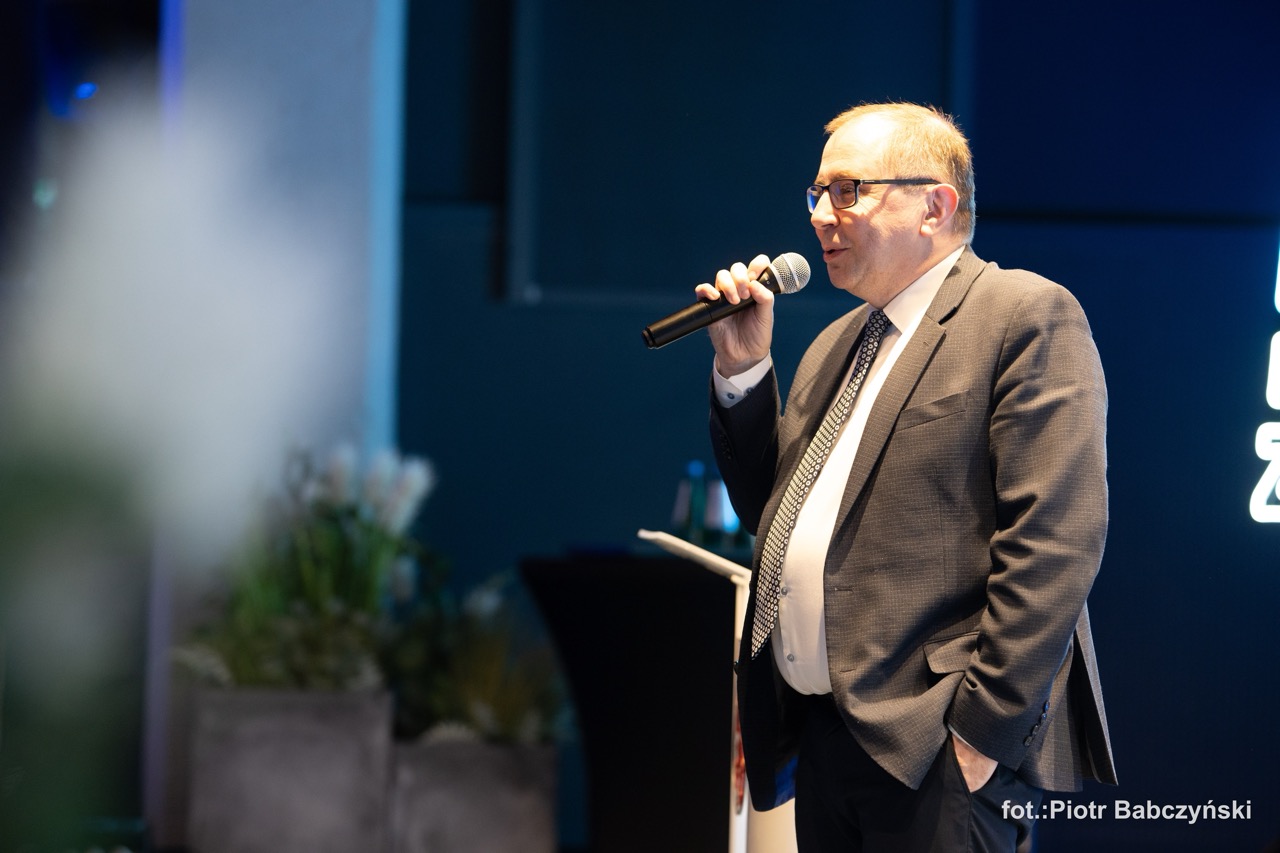 Prezentacja prelegenta podczas wydarzenia BusinessContact6 w Szczecinie, z mikrofonem w dłoni.
