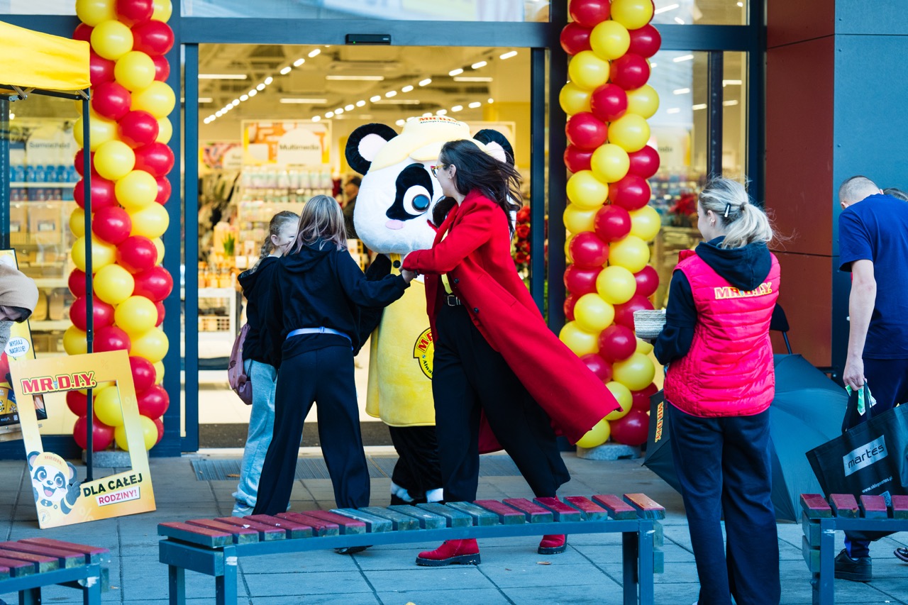 Ceremonia otwarcia sklepu MR. D.I.Y w Szczecinie z maskotką w panda oraz radosnymi klientami przy wejściu.