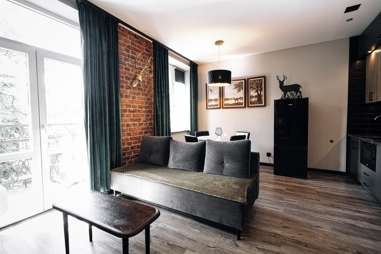 Stylowe wnętrze apartamentu w Zakopanem z ceglaną ścianą, sofą i eleganckim oświetleniem.