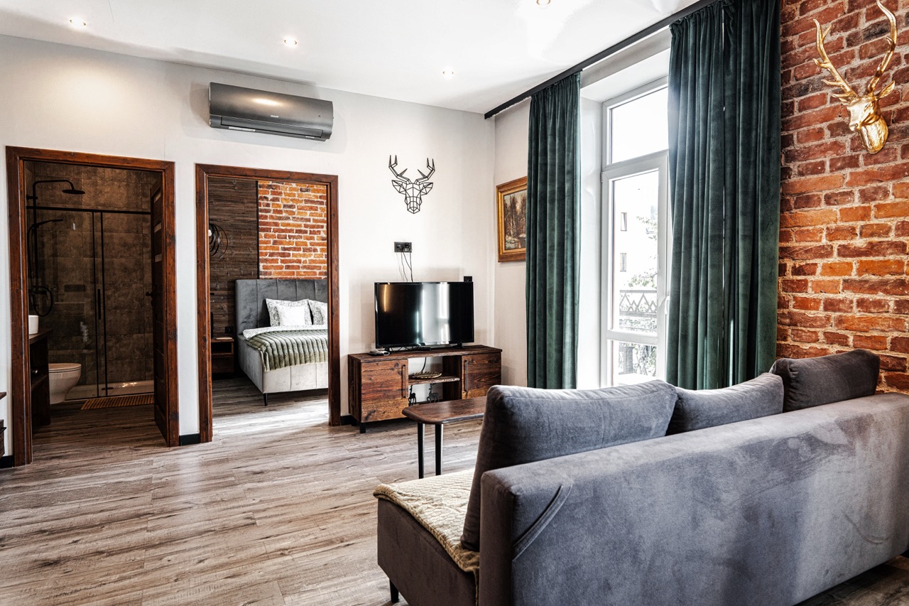 Fotografia wnętrz apartamentu w Zakopanem — widok na salon z telewizorem i sypialnią w tle.