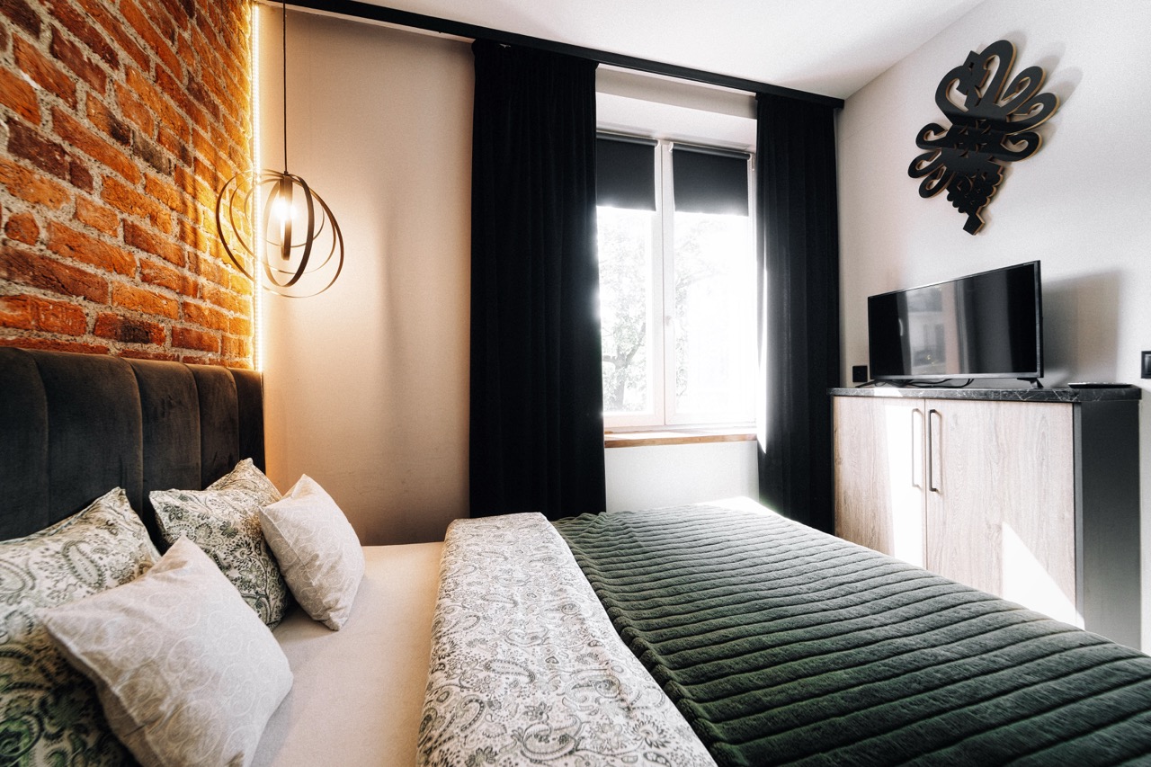 Stylowe wnętrze sypialni w apartamencie w Zakopanem z ceglaną ścianą i nowoczesnym oświetleniem.