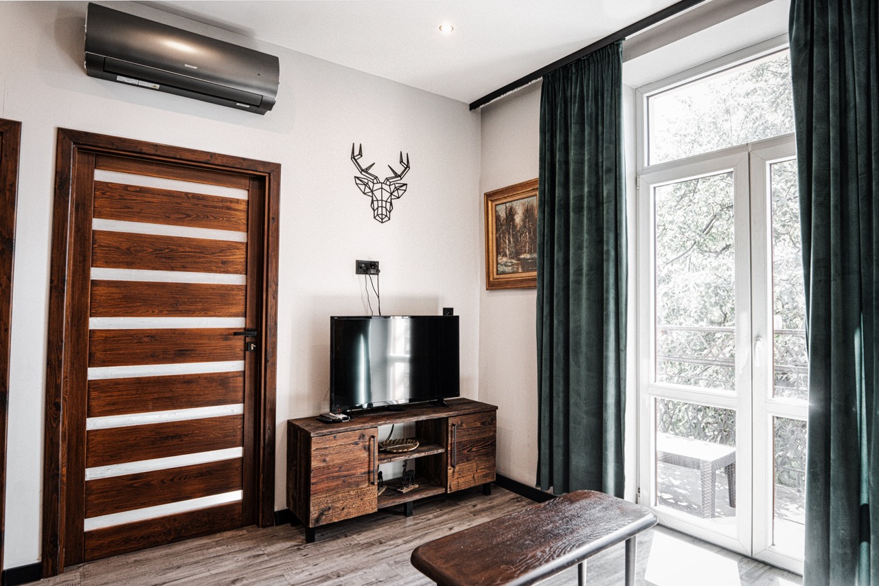 Fotografia wnętrz apartamentu w Zakopanem — nowoczesny salon z telewizorem i drewnianymi akcentami.