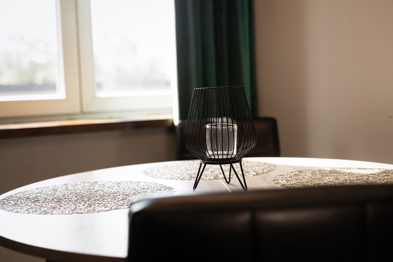 Stylowe wnętrze apartamentu w Zakopanem z okrągłym stołem i nowoczesną lampą na tle okna.