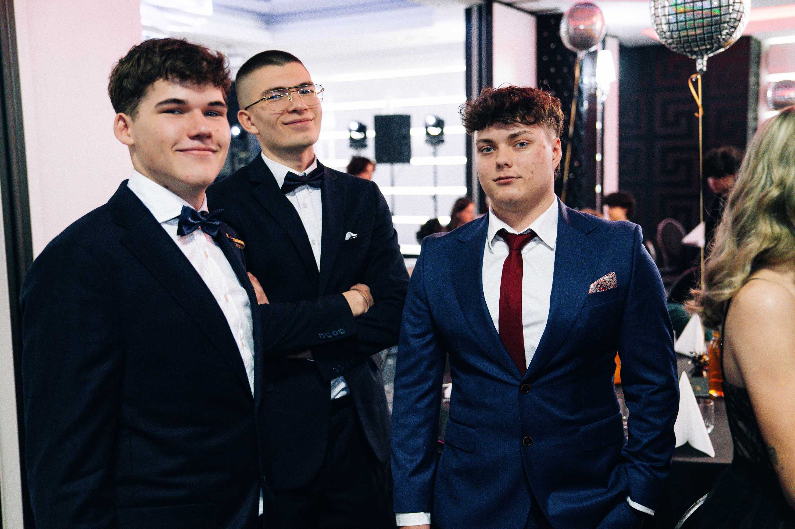 Trzech młodych mężczyzn w eleganckich garniturach podczas studniówki w Hotelu Dana w Szczecinie.
