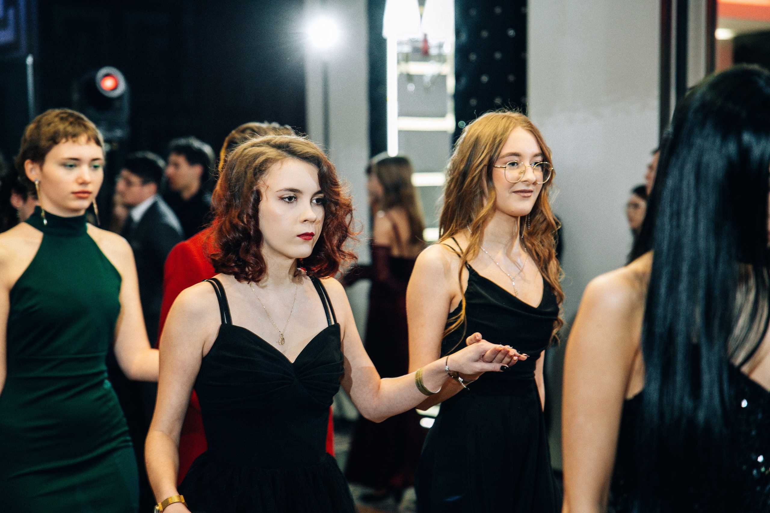 Fotografia studniówkowa w Szczecinie — uczestniczki w eleganckich sukienkach w trakcie tańca w Hotelu Dana.