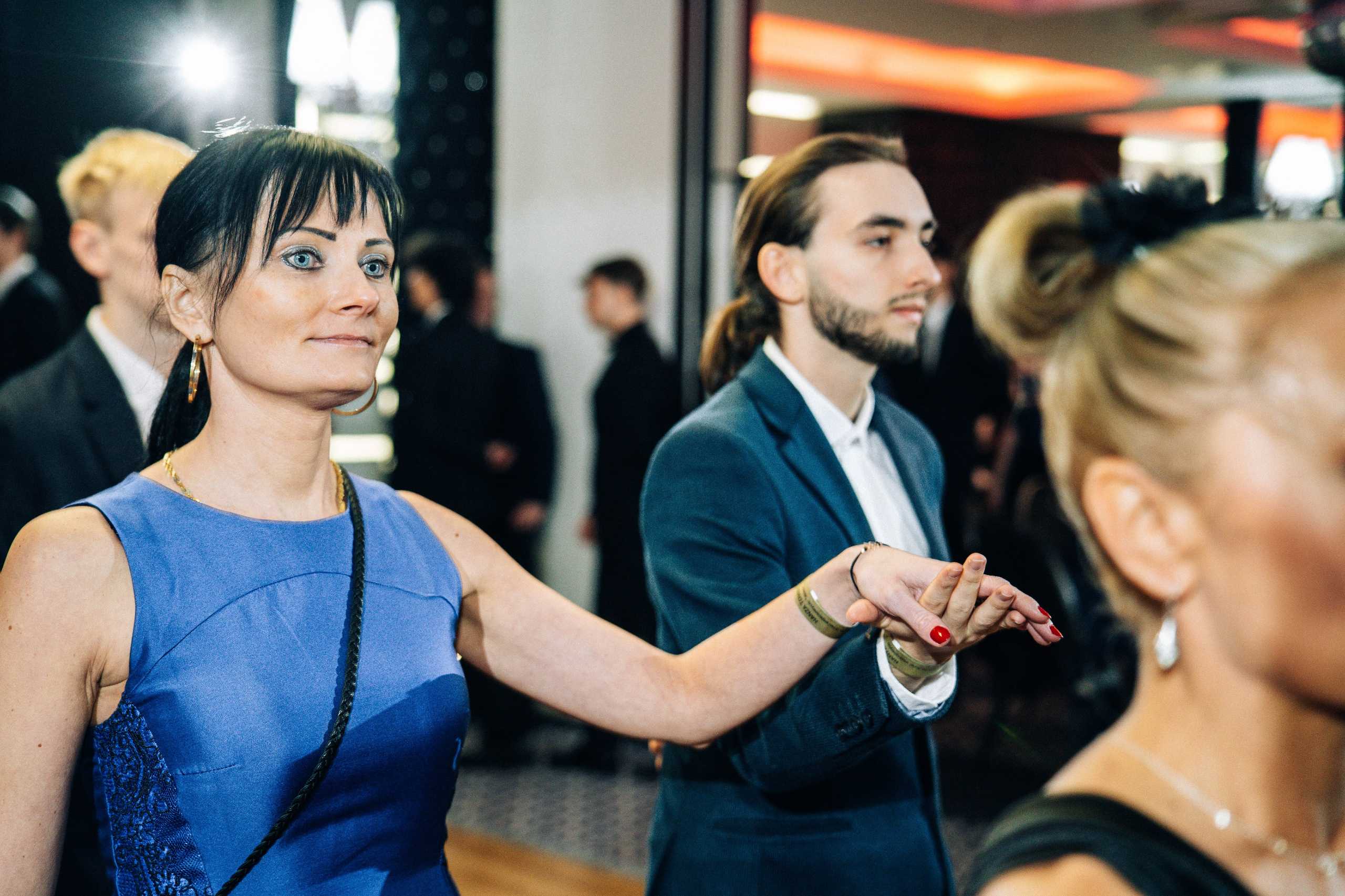 Uczestnicy studniówki w Hotelu Dana w Szczecinie, kobieta w niebieskiej sukience trzyma rękę mężczyzny w garniturze.