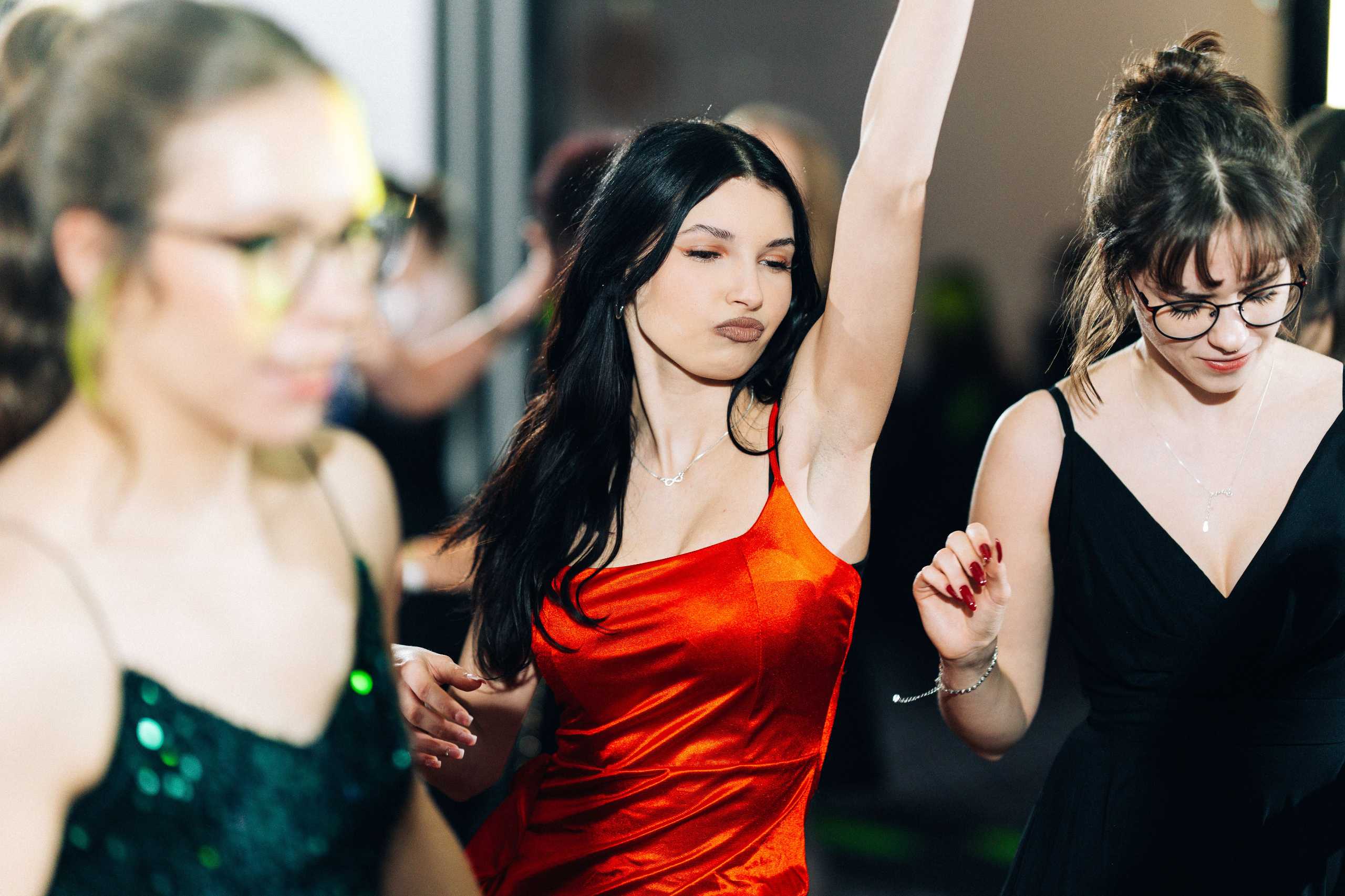 Fotografia studniówkowa w Szczecinie — młoda kobieta w czerwonej sukience tańczy na parkiecie w Hotelu Dana.