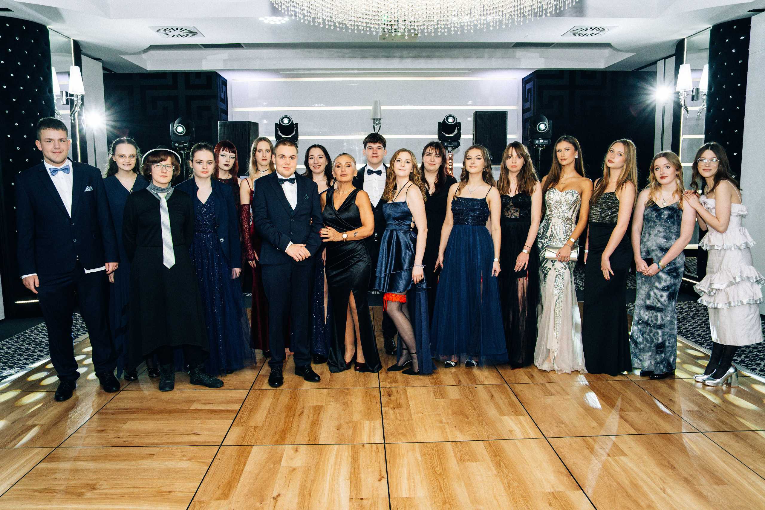 Grupa młodych ludzi w eleganckich strojach na studniówce w Hotelu Dana w Szczecinie, pozująca na parkiecie.