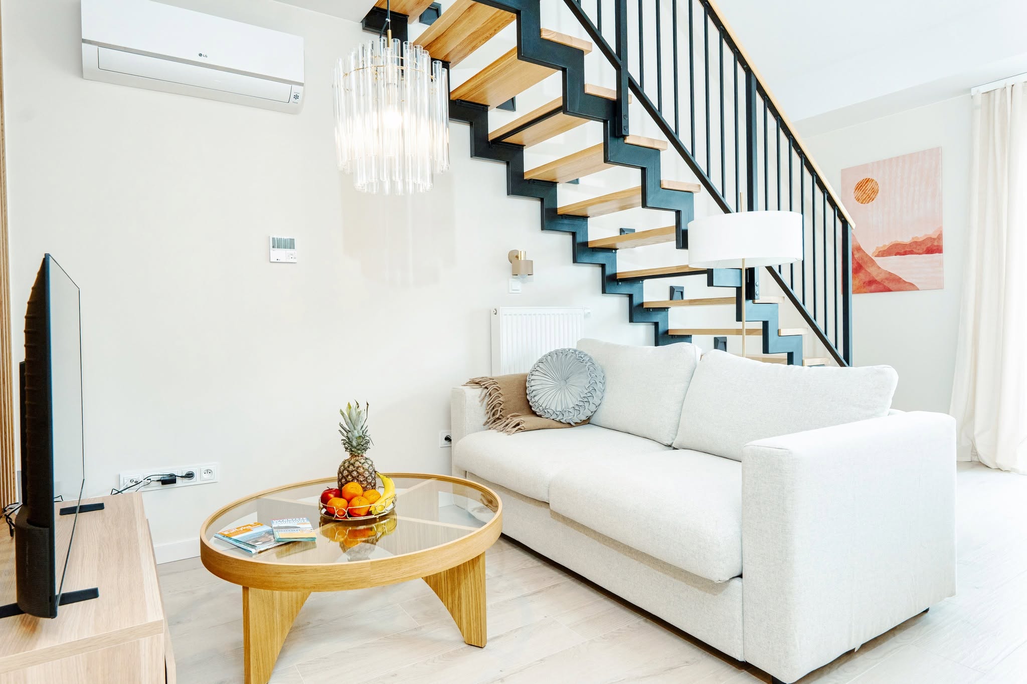 Fotografia wnętrza apartamentu w Niechorzu — przestronny salon z nowoczesnym wystrojem i schodami.